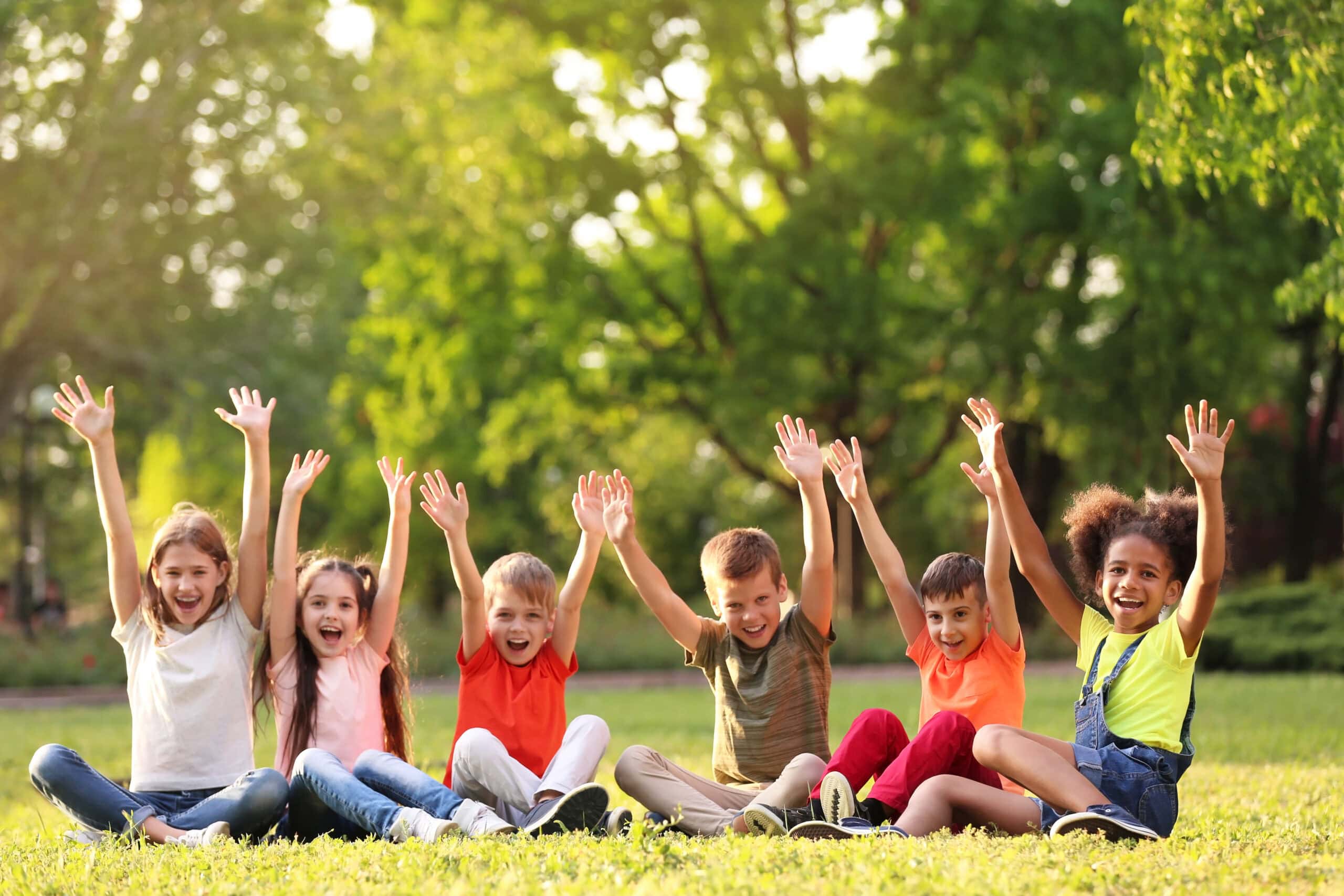 Cute little children sitting on grass outdoors