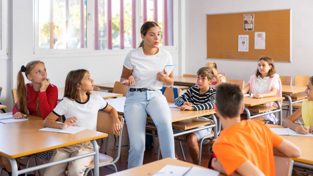 Teacher reading lecture to schoolkids in classroom